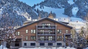 A multi-story hotel with a modern design, located in a snowy mountainous area with ski slopes visible in the background. - W Aspen (Aspen)