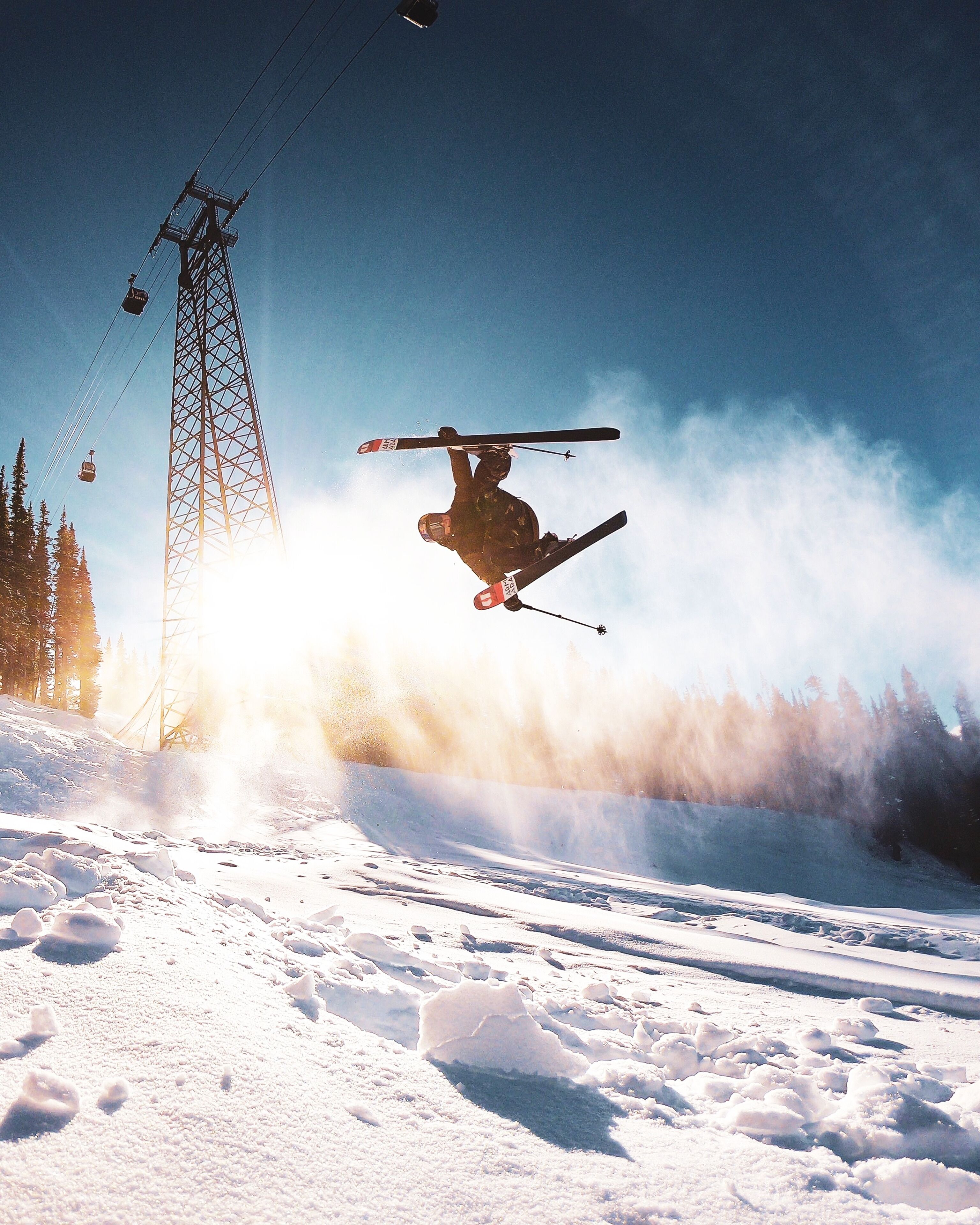 A ski lift tower and a skier performing a jump.