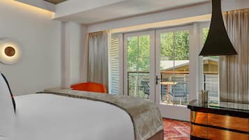 A hotel room with a bed, a desk, a chair, and a large window with blinds.