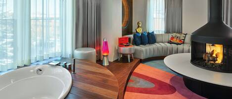 A modern living room with a fireplace, a sofa with blue cushions, and a round coffee table.
