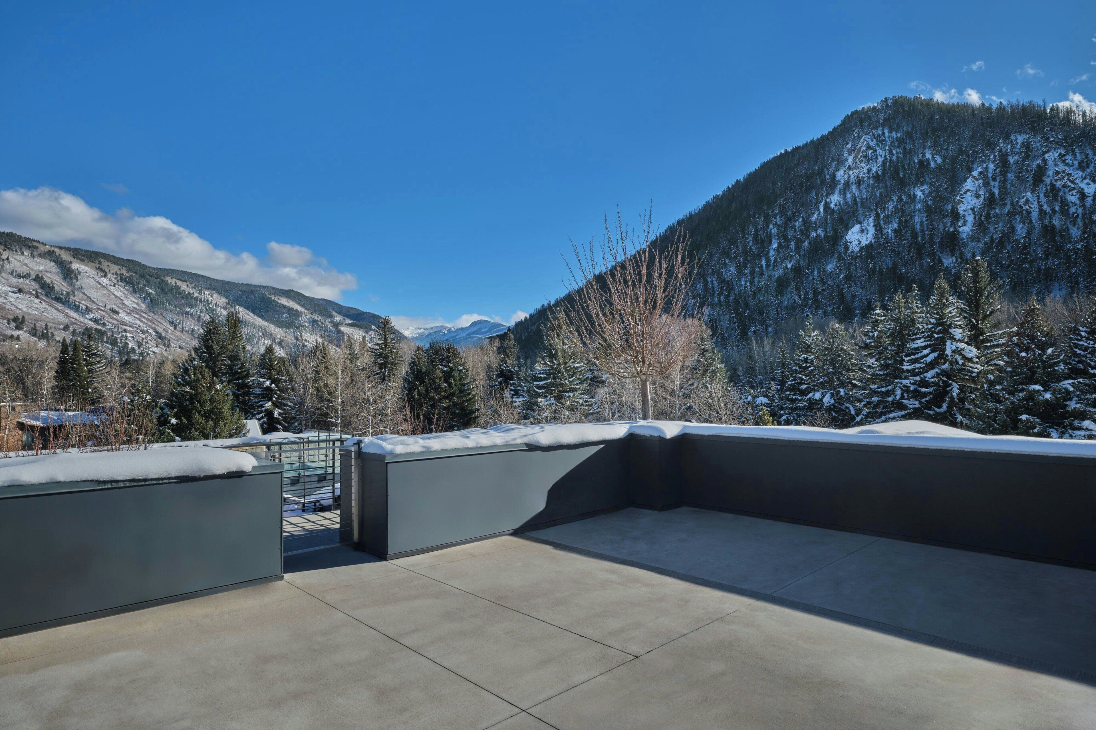 Una terrazza sul tetto con vista su montagne innevate e un cielo sereno.