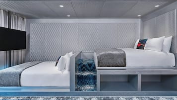 Una habitación de hotel moderna con una cama grande, una cama más pequeña, un televisor de pantalla plana y un papel tapiz estampado.