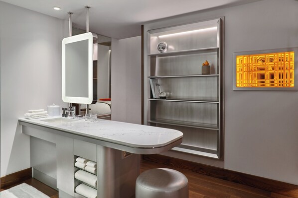 A modern bathroom with a marble sink, a large mirror, and a shelf with decorative items.