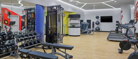 A modern gym with various exercise equipment, including treadmills, weight machines, and free weights.
