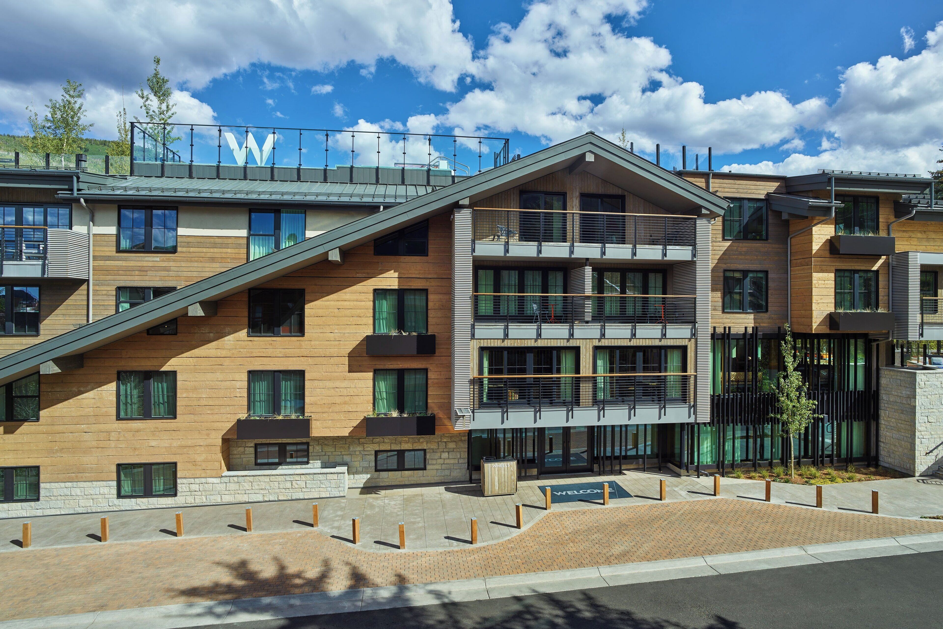 A modern multi-story building with a prominent 'W' logo on the roof, large windows, and a landscaped courtyard.