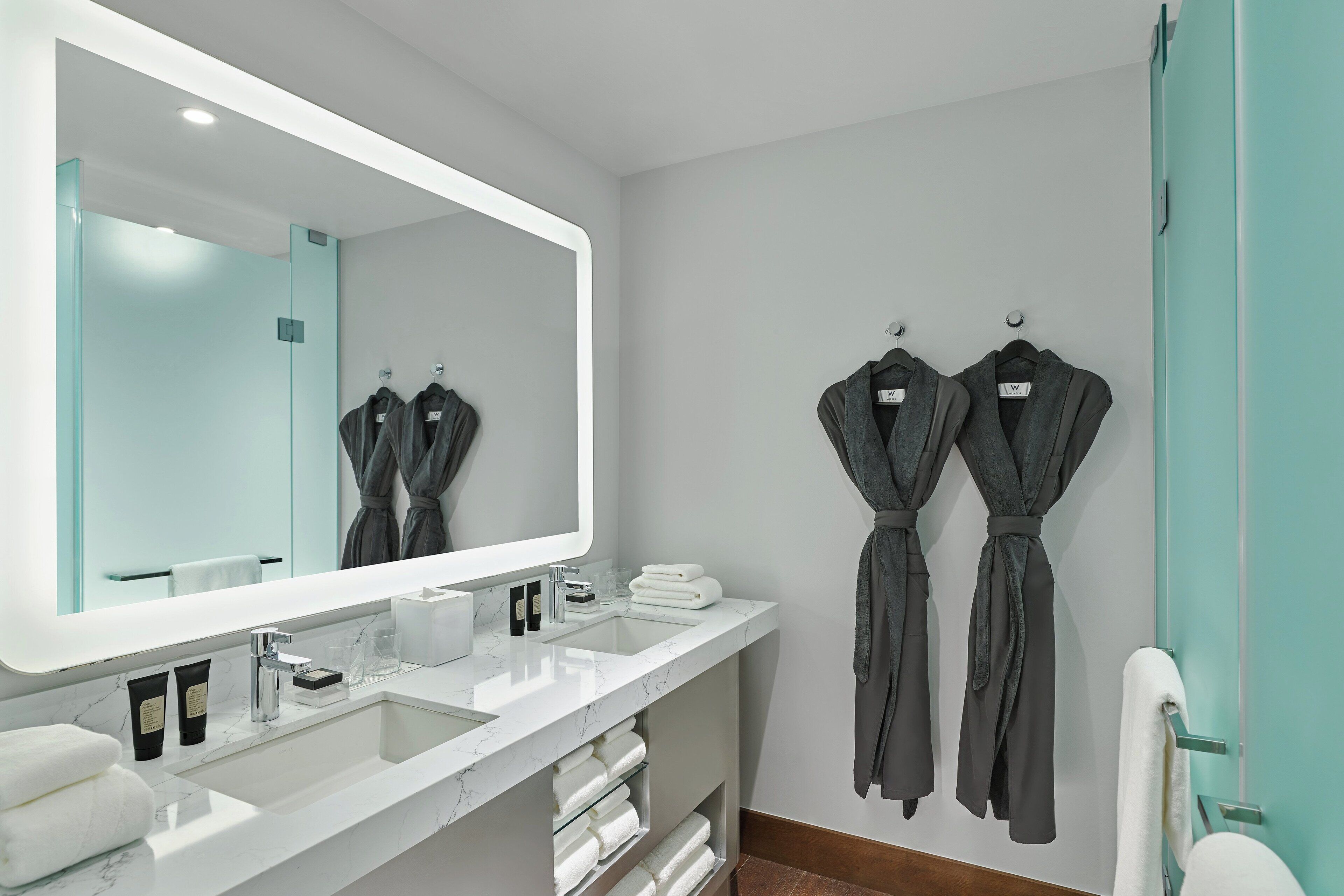A modern bathroom with a large mirror, two sinks, and a glass shower enclosure.