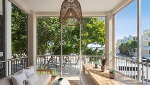 A balcony with a sofa, wooden table, and hanging light fixture. - Marina Villa  212 3/3 Pools, Marina and Ocean views (Key Largo)