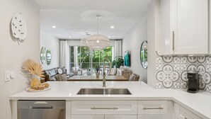 A modern kitchen with white cabinetry, a stainless steel sink, and a coffee maker. - Marina Villa  212 3/3 Pools, Marina and Ocean views (Key Largo)