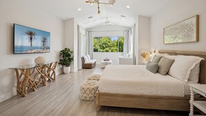 A spacious bedroom with a large bed, a glass desk, a potted plant, and a view of the outdoors. - Marina Villa  212 3/3 Pools, Marina and Ocean views (Key Largo)