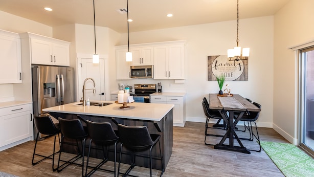 A modern kitchen with white cabinetry, stainless steel appliances, a central island with bar stools, and a dining table with chairs. - Luxury Zion Escape sleeps 12 *Private Hot Tub* (Washington)