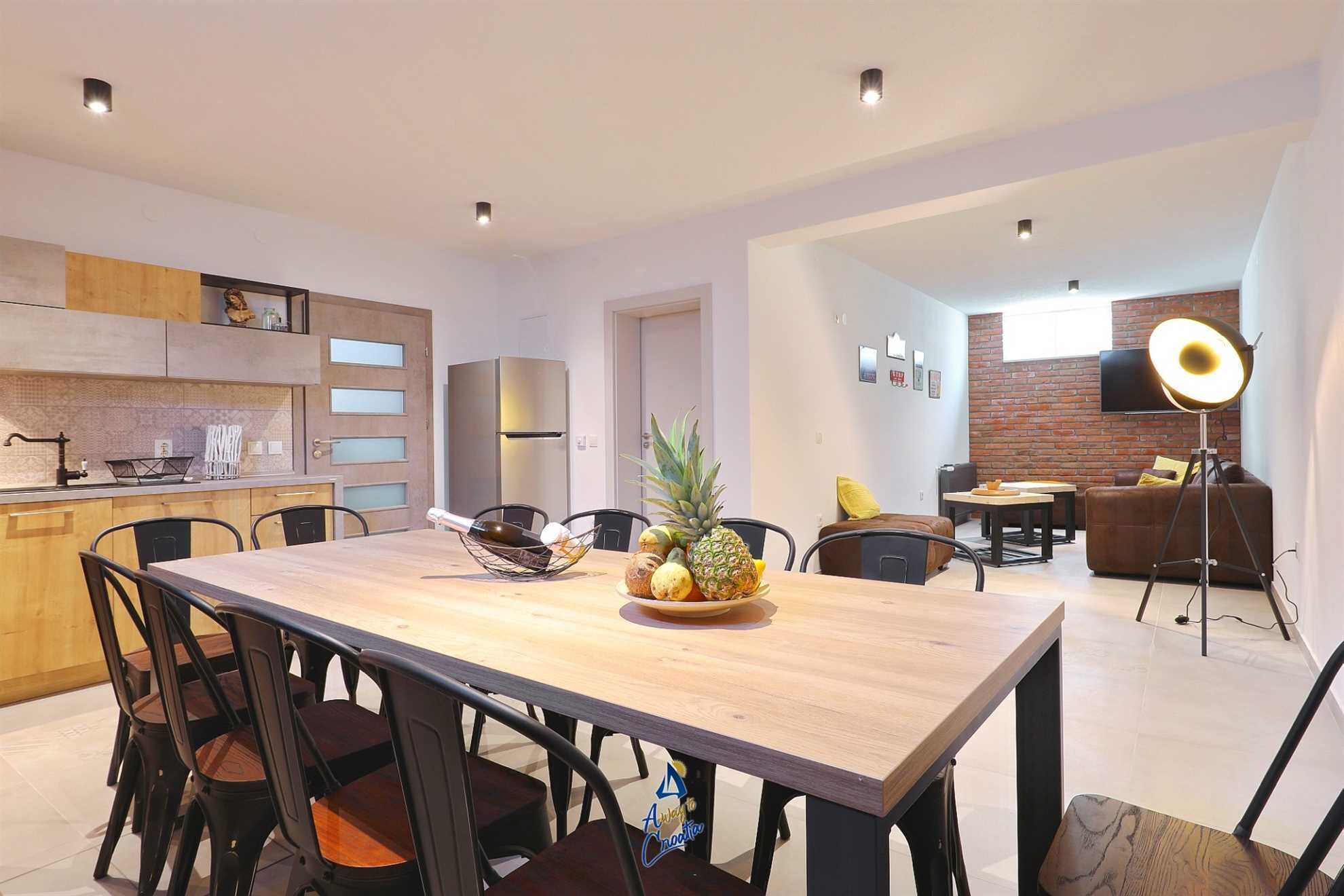 Una cucina moderna con zona pranzo, TV a schermo piatto e un'accogliente area salotto con lampada.
