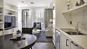 Een moderne keuken met witte kasten, een inbouwgootsteen en een eethoek met een ronde tafel en stoelen.