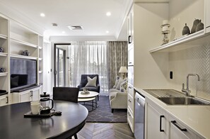 A modern kitchen with white cabinetry, a built-in sink, and a dining area with a round table and chairs.