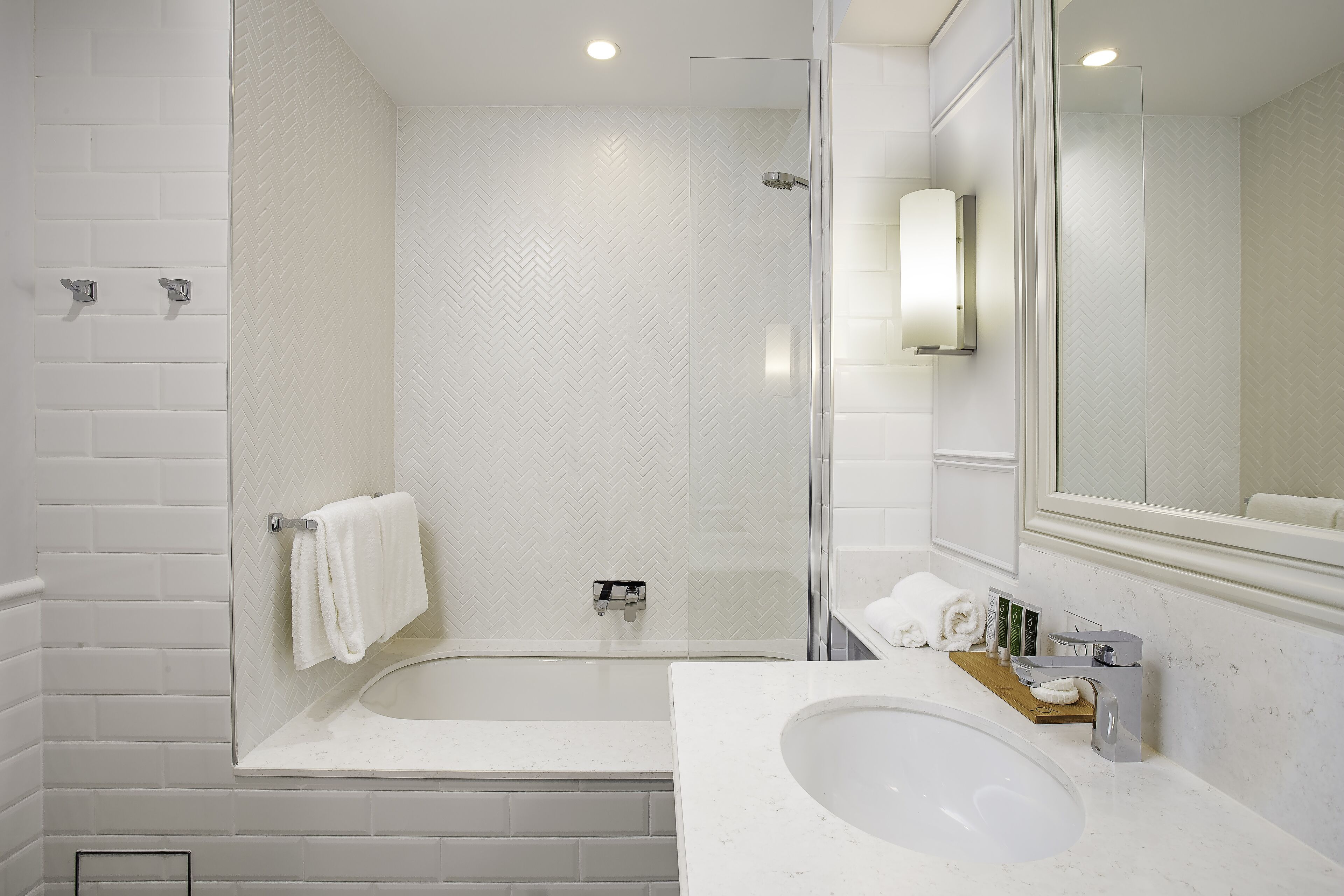 A modern bathroom with a glass-enclosed shower, a large bathtub, and a sink with a marble countertop.