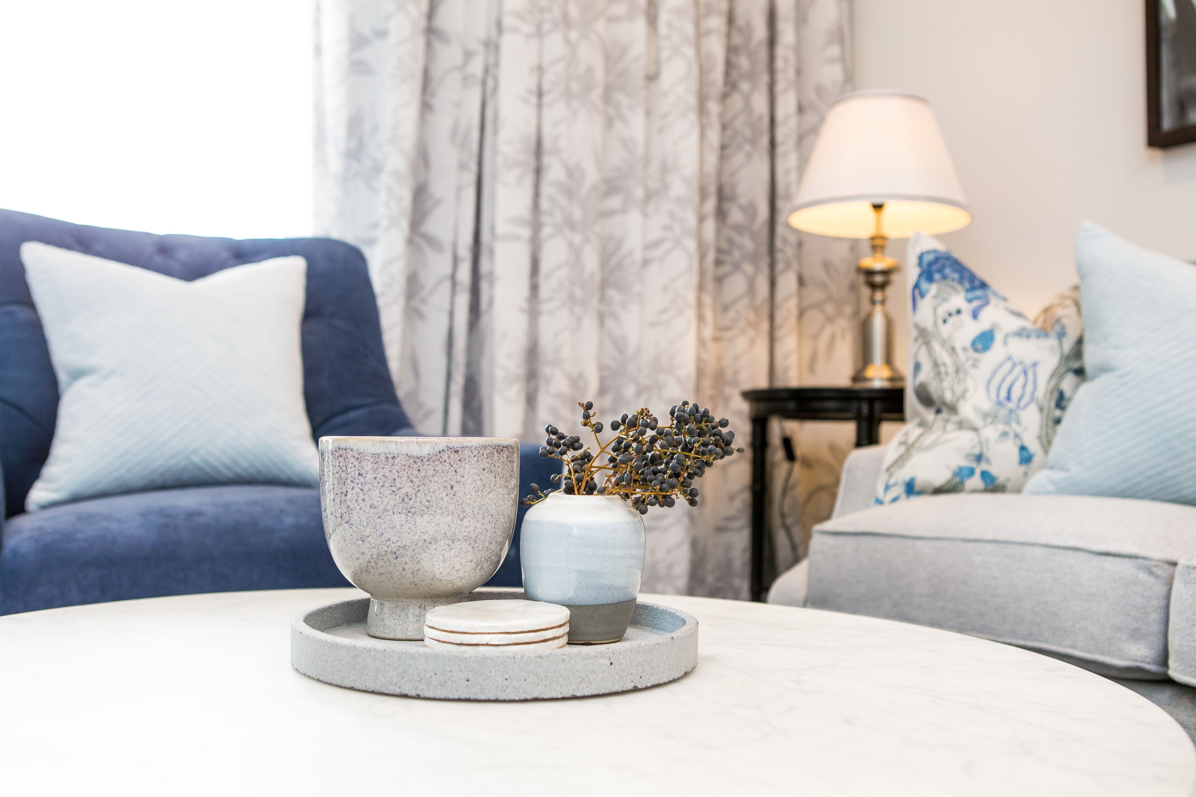 A living room with a round coffee table, a blue sofa, and a grey sofa.