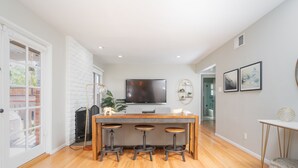A modern kitchen with a central island, bar stools, a large flat-screen TV, and a fireplace.