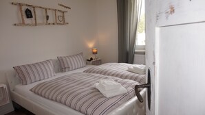 Una camera da letto con due letti, un comodino con una lampada, una decorazione a forma di scala in legno e una porta bianca.