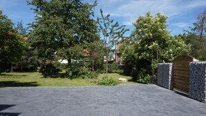 Una strada asfaltata che conduce a un cancello con muro in pietra, immersa nel verde e alberi.