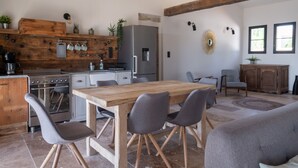 Une cuisine moderne avec une table et des chaises en bois, un réfrigérateur et une cuisinière.