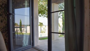 Une porte vitrée donne accès à un patio extérieur agrémenté d’une piscine et de verdure.