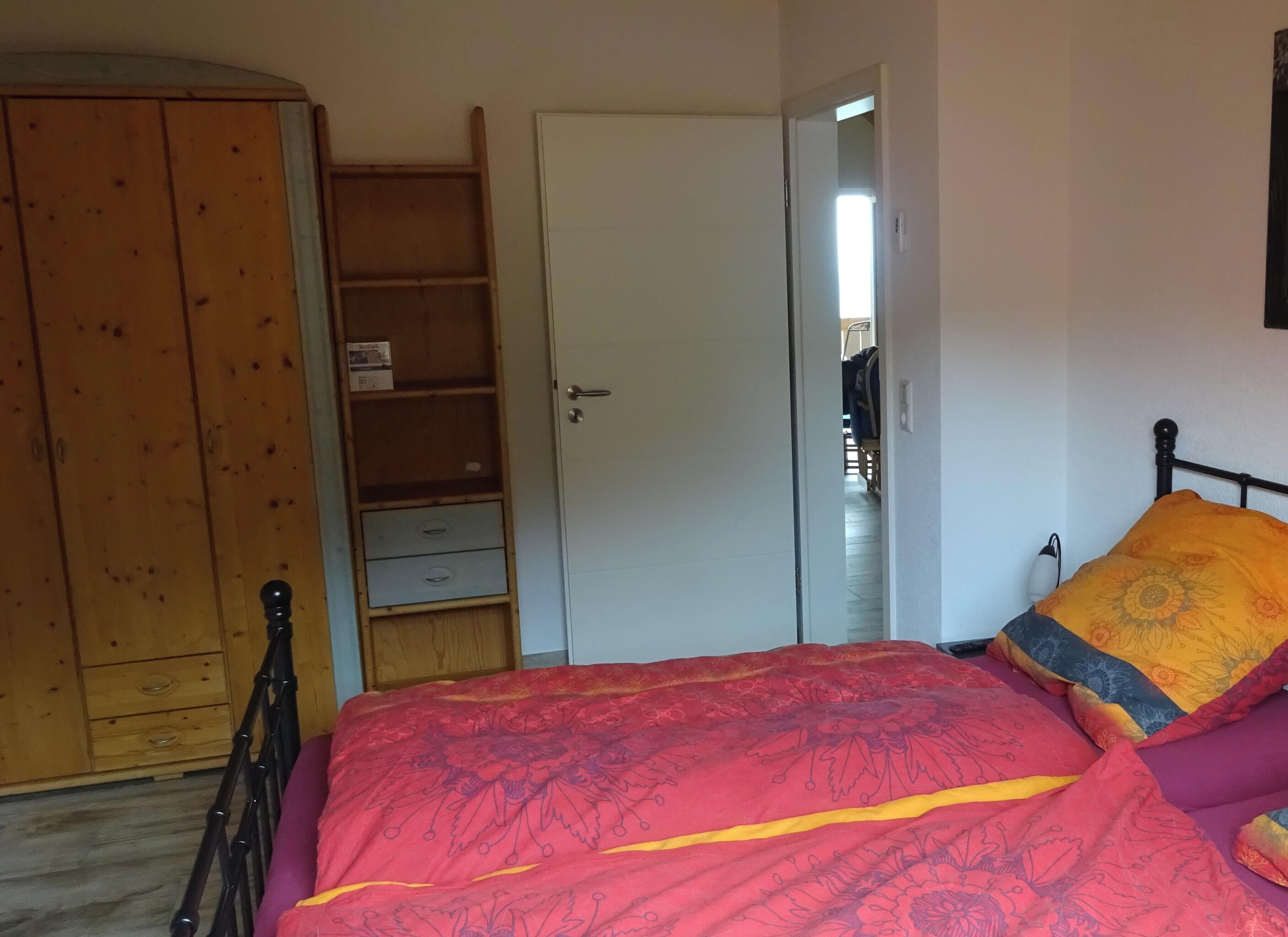 Un dormitorio con una cama, un armario y una puerta que da a otra habitación.
