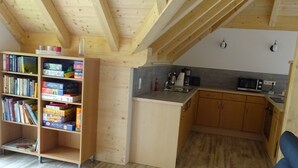 Una cocina acogedora con vigas de madera, una estantería llena de libros y un pequeño comedor.