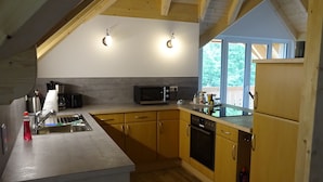 Una cocina con armarios de madera, un lavamanos de acero inoxidable, un microondas y un refrigerador.