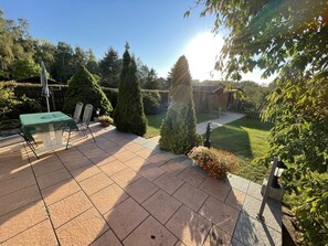A patio with a table and chairs, surrounded by neatly trimmed hedges and a lawn. - Holiday house at Birkenwäldchen - Motzener See 150m (Motzen)