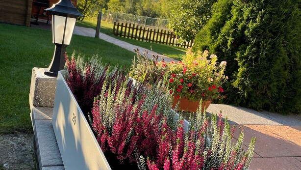 A garden with a planter bed, a lamp post, and a wooden fence. - Holiday house at Birkenwäldchen - Motzener See 150m (Motzen)