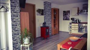 A modern kitchen with a red cabinet, a built-in oven, and a coffee maker. - Holiday house at Birkenwäldchen - Motzener See 150m (Motzen)