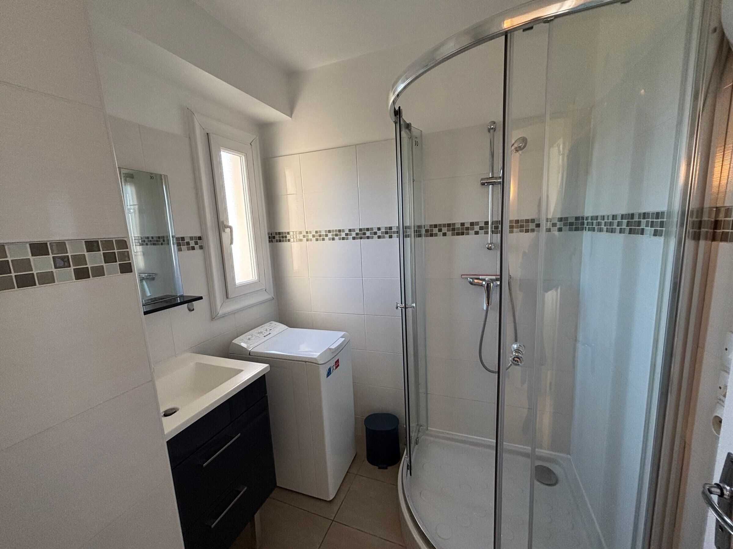 Un bagno con cabina doccia in vetro, lavandino, WC e specchio.