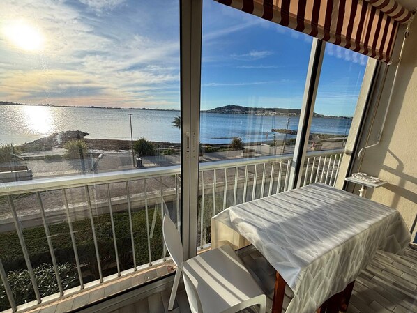 A balcony with a view of a body of water and a distant island.