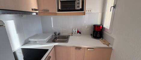 A compact kitchen with a microwave, coffee maker, and a sink.