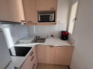 A compact kitchen with a microwave, coffee maker, and a sink.