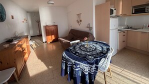 Ett kompakt bostadsutrymme med en matplats, ett litet kök och en soffa.
