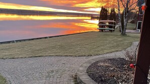 A paved walkway leading to a grassy area with a wooden deck and a bench. - Riverside Retreat, sit back and relax...:-) (Sault Ste. Marie)