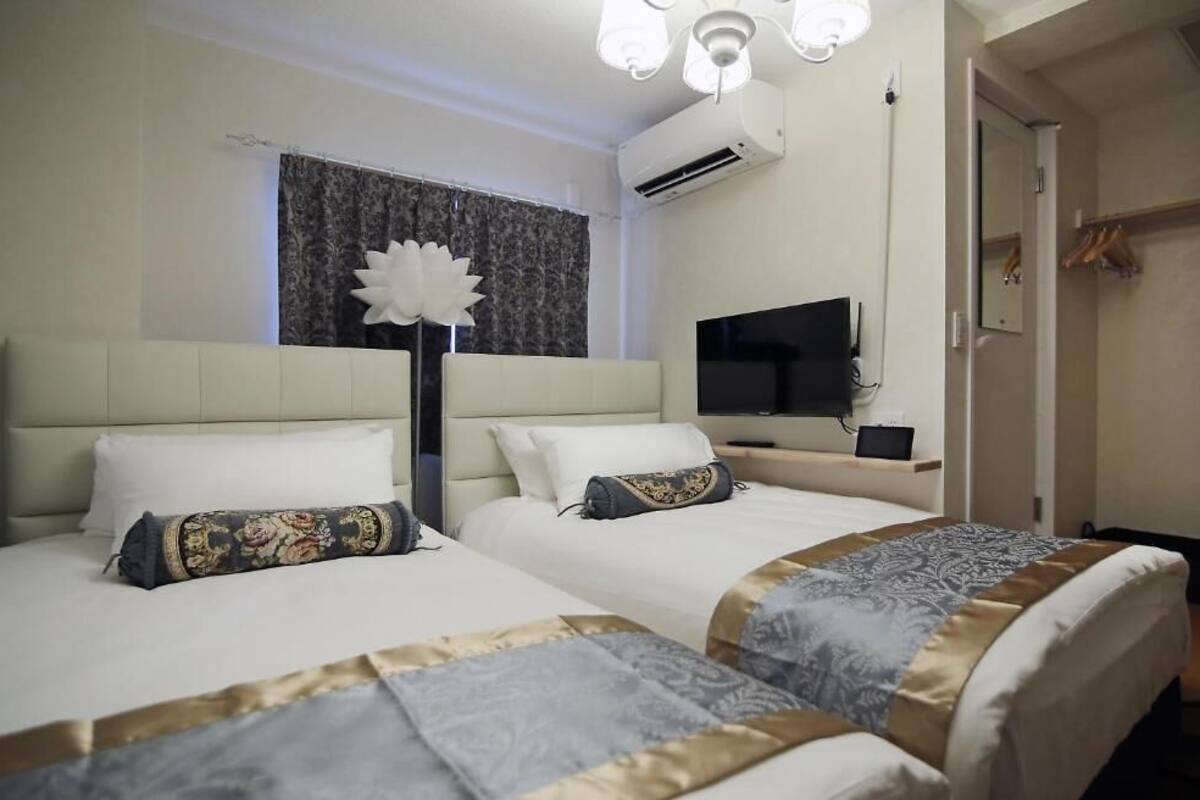 Ett hotellrum med två sängar, en platt-TV, en luftkonditioneringsanläggning och en garderob.