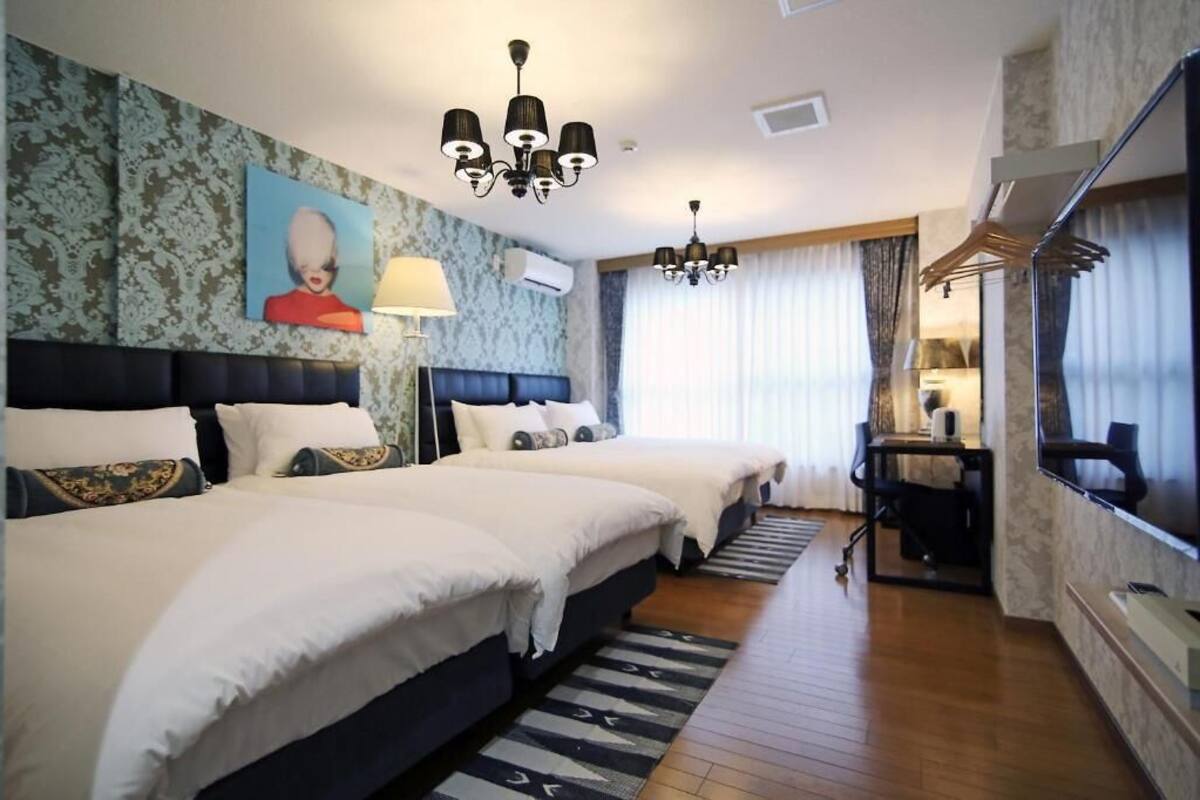 Ett hotellrum med två sängar, en TV, ett skrivbord och en kristallkrona.