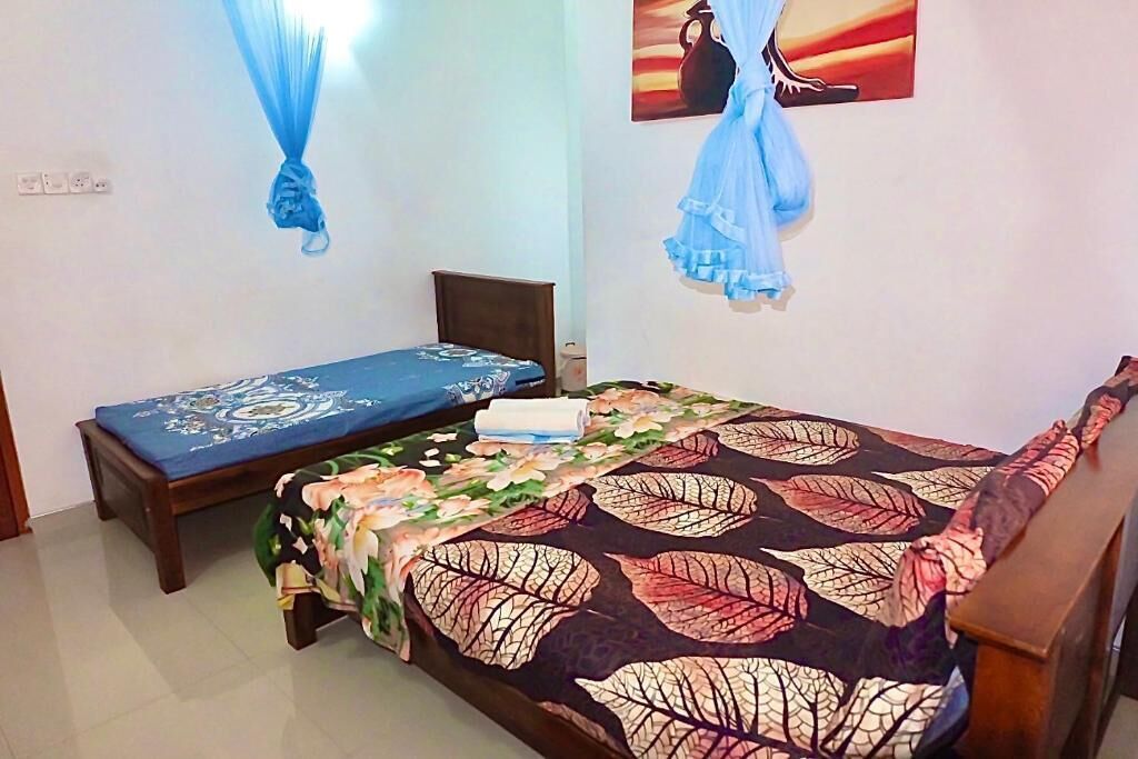 A bedroom with a bed, a small table, and a wall-mounted shelf.