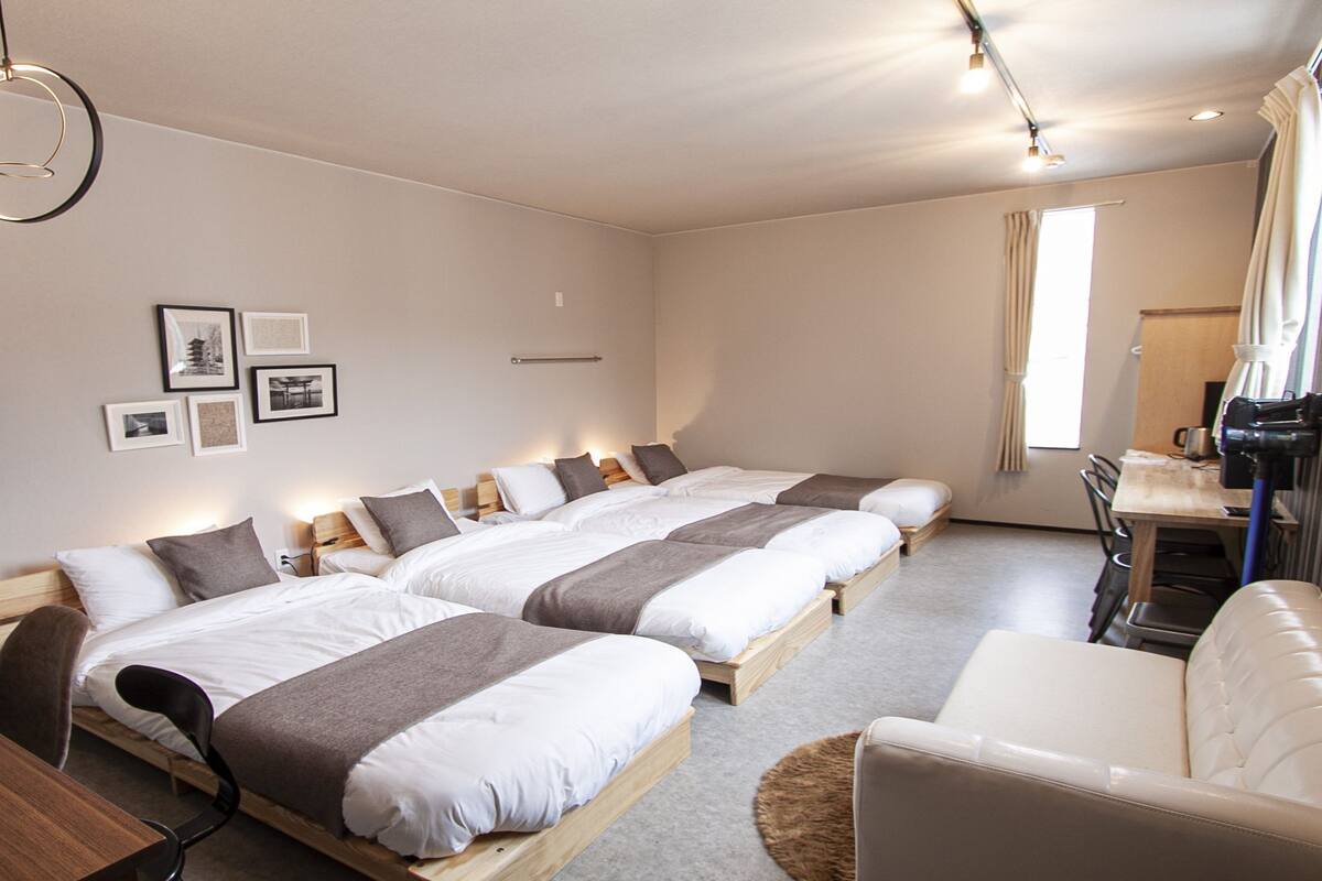 A hotel room with two beds, a TV, a desk, and a chair.