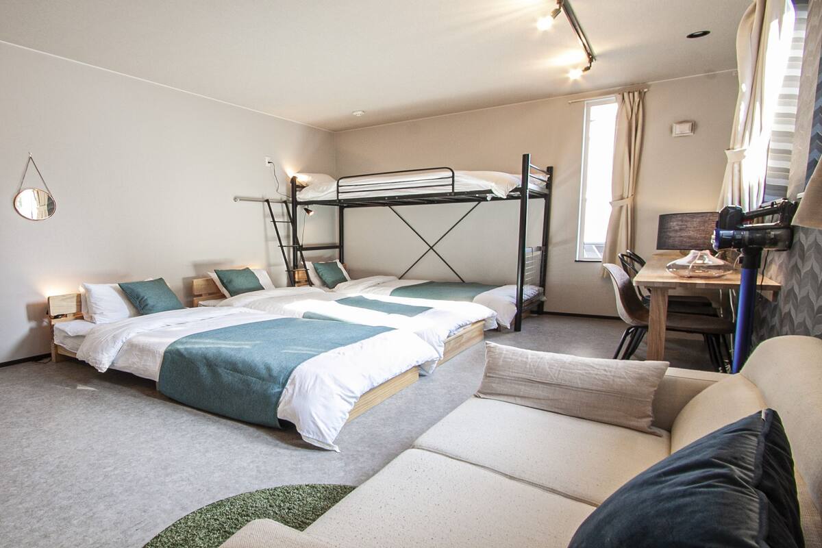 A hotel room with a bunk bed, a flat-screen TV, a desk with a chair, and a sofa.