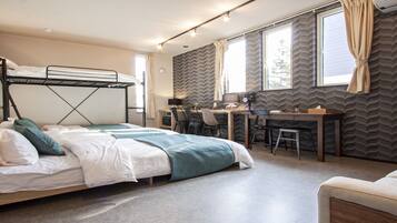 A bunk bed with a desk and chair, a sofa, and a window with curtains.