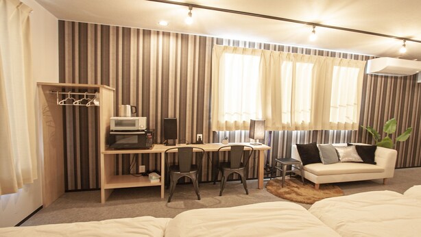 Ein Hotelzimmer mit einem Bett, einem Schreibtisch mit Computer, einem Sessel und einer Zimmerpflanze.