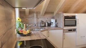 A modern kitchen with wooden beams, a stainless steel sink, a built-in oven, and a coffee maker.