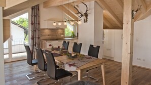 A dining area with a wooden table, black chairs, and a rustic ceiling.