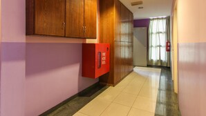 Un pasillo con armarios de madera, un carrete de manguera roja y una puerta que da a otra habitación.
