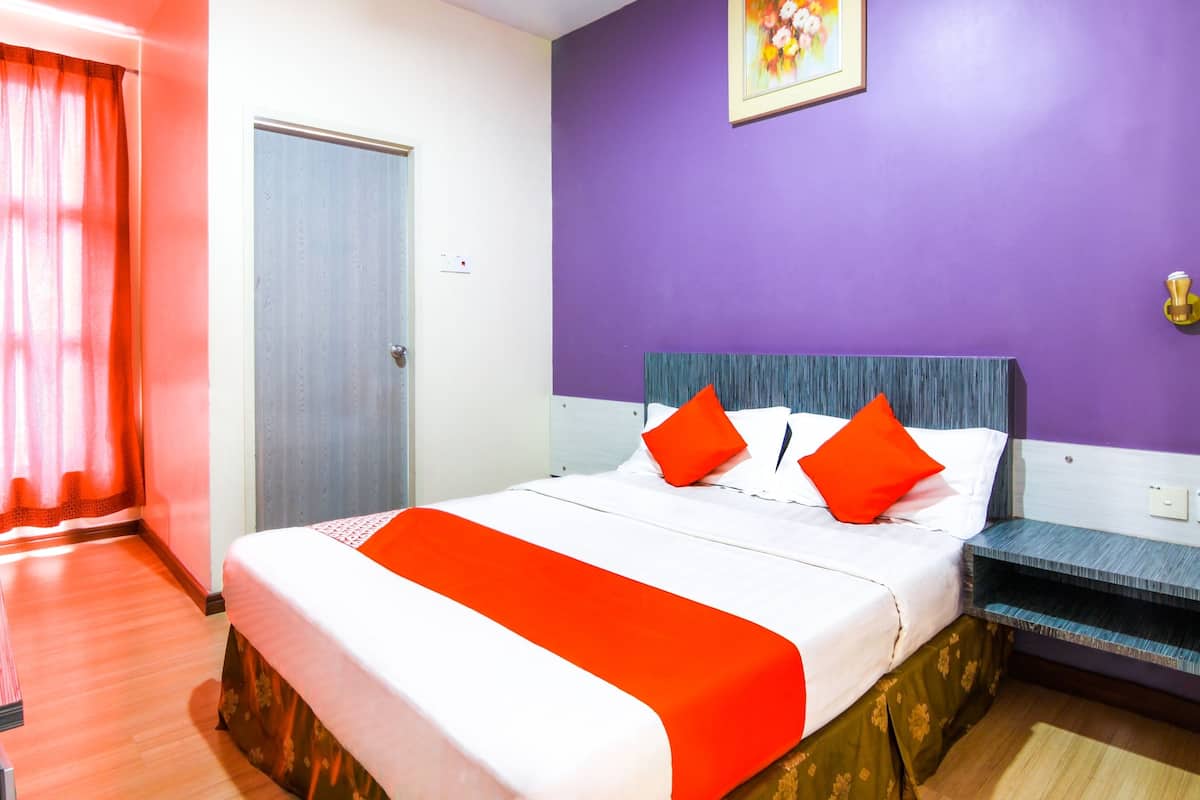 Una habitación de hotel con cama, puerta, ventana con cortinas y un cuadro en la pared.
