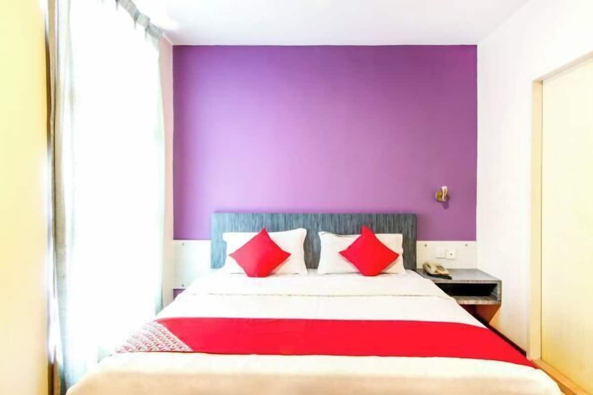 Una habitación de hotel con una cama, una mesita de noche y un teléfono.