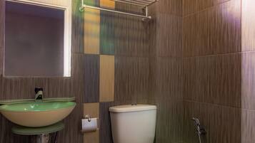 Un bagno con il water, un lavandino e un portascopevoli.