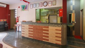 Zona de recepción con mostrador de salida, extintor, escritorio de recepción y panel de control fijado a la pared.